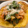 Stuffed spaghetti squash halves filled with chicken, tomatoes, kale, and topped with Parmesan and fresh basil.