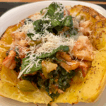 Stuffed spaghetti squash halves filled with chicken, tomatoes, kale, and topped with Parmesan and fresh basil.