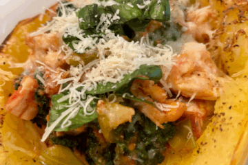 Stuffed spaghetti squash halves filled with chicken, tomatoes, kale, and topped with Parmesan and fresh basil.