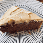 Close-up of a slice of almond flour banana cake with cashew butter frosting on a patterned plate