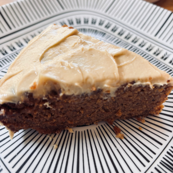 Close-up of a slice of almond flour banana cake with cashew butter frosting on a patterned plate