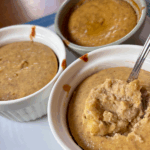 Pumpkin Cheesecake Cups in ramekins, one with a spoonful taken out