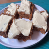 SCD carrot cake bars with yogurt cream cheese frosting on a white plate, showing the moist grain-free bars topped with thick creamy frosting