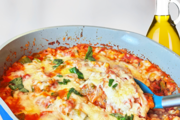 Grain-free pizza beans baked with tomato sauce, bell peppers, melted cheese, and fresh basil in a blue skillet.