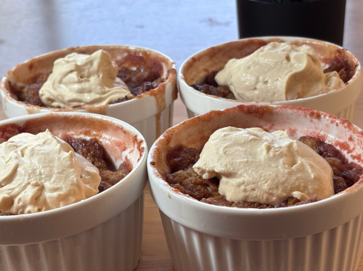 Four white ramekins of strawberry rhubarb crisp topped with dollops of SCD yogurt made with heavy cream, served on a wooden surface.